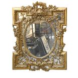 A giltwood and composition mirror, the frame decorated with flowers and foliage, the central oval