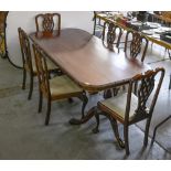 A carved mahogany dining table, on twin pedestal base and claw and ball feet and a set of six