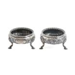 A pair of Victorian silver salt cellars, chased with flowers, on three hoof feet, 70mm diam, by