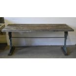 A garden table,  the substantial weathered three plank top on ornate Victorian cast iron trestles