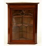 A George III mahogany hanging corner cupboard, with arch patterned glazing bars to the door, 109cm