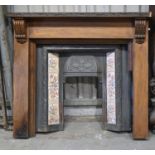 A carved and stained wood chimneypiece and a Victorian tiled cast iron hooded fire surround,