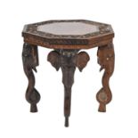 An Indian rosewood table, early 20th c, the carved octagonal top with floral border on four elephant