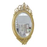 A Victorian oval giltwood and composition mirror, with bevelled plate and crested by a Venus