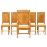 A set of five light oak panel back chairs, mid 20th c, including an armchair with brass memorial