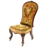 A Victorian rosewood nursing chair, the padded back in moulded frame crested by a carved flower,