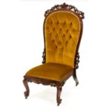 A Victorian rosewood nursing chair, the buttoned back in moulded frame with leafy scrolling crest