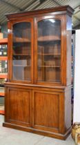 A Victorian mahogany bookcase, c. 1860, moulded outswept cornice above a pair of glazed doors