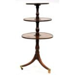 A George III mahogany dumb waiter, of three tiers with baluster shaft, on tripod with plain brass