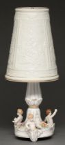 A German porcelain table lamp and shade, the base decorated with three cherubs, 51cm h Minor chips