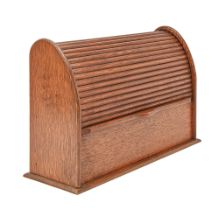 An oak stationery box, c. 1920, sliding tambour front enclosing graduated divisions, skirted base,