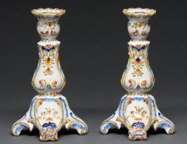 A pair of French faience candlesticks, 20th c, on four scroll feet, 24cm h Good condition