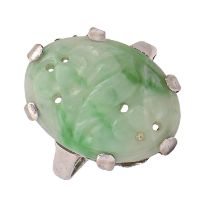 A jadeite ring, c1930, the oval plaque carved and pierced with a bird on a branch, in white gold