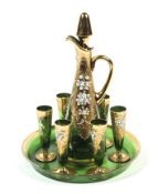 An Italian gilt and enamelled green glass decanter, stopper, circular tray and six glasses.