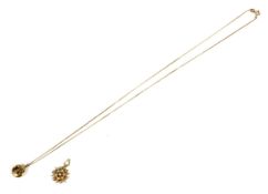 A yellow metal starburst pearl pendant and a gold pendant, on a gold necklace.
