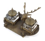 A brass desk stand with central stag's head flanked by two ink wells, enclosed by stacked logs,
