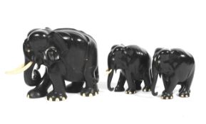 Three mid-20th century carved ebony models of elephants with bone tusks.