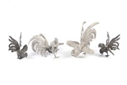 Four white metal models of fighting cocks.