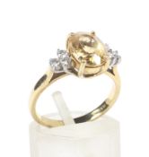 A yellow topaz dress ring. The centre stone flanked by six diamonds.