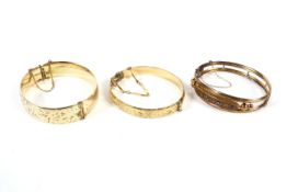 Three assorted bangles two with engraved decoration.