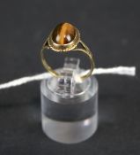A 9ct gold ring set with an oval cabochon tigers eye gemstone. Size N, 2.