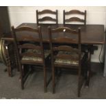 A mid-century stained wooden dining table and four ladder back dining chairs.