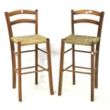 A pair of wooden framed wicker seated stools.