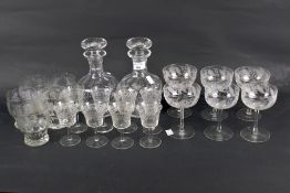 An assortment of engraved drinking glasses and two decanters.