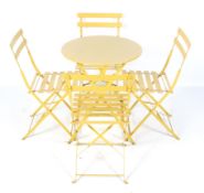 A yellow painted metal folding patio table and four chairs.