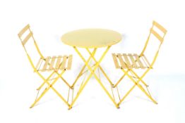 A yellow painted metal folding patio table and two chairs.