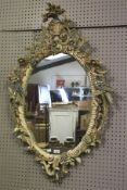 An ornate 20th century oval wall mirror. Frame with birds and floral decoration. 120 x 76cm.