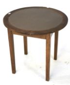 A 20th century oak table. Of circular form with a leather insert top, raised on tapering supports.