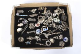 A collection of silver and white metal brooches and pins.