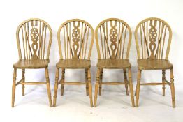 A set of four stripped wheel back dining chairs on turned tapering legs.
