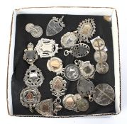 An assortment of vintage silver and white metal sports medals and brooches.