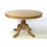 An oak circular dining table on single pedestal.