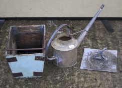 A vintage metal watering can, a sundial and a wooden basket with a single handle.