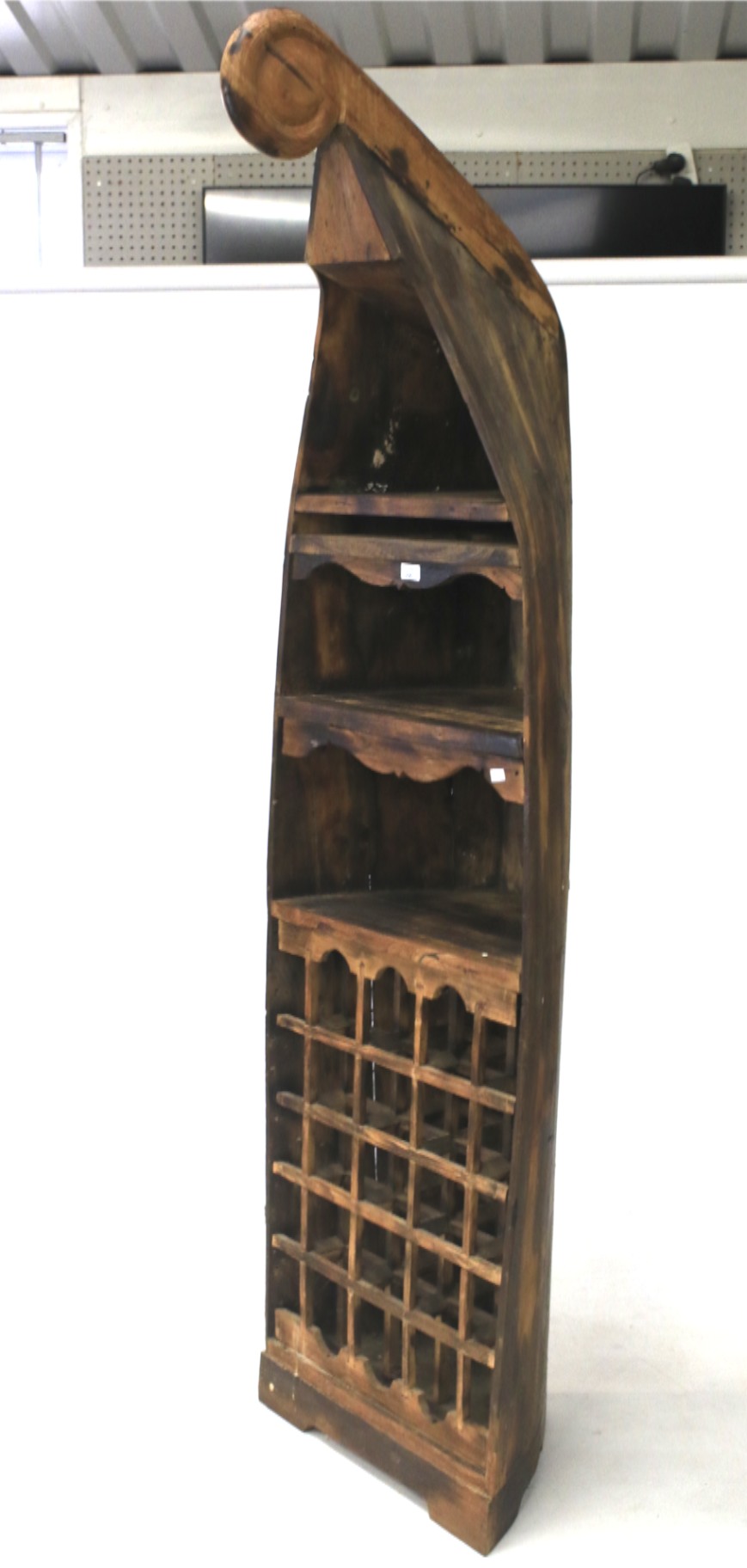 A stained pine wine rack in the form of half a dug-out canoe.