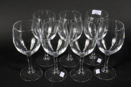 A set of seven large red wine glasses.