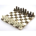 A brown and white marble chessboard and a matching full chess set.