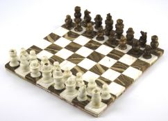 A brown and white marble chessboard and a matching full chess set.