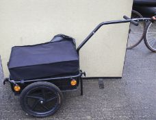 A steel framed cycle trailer with black plastic wheel, box and fabric cover.