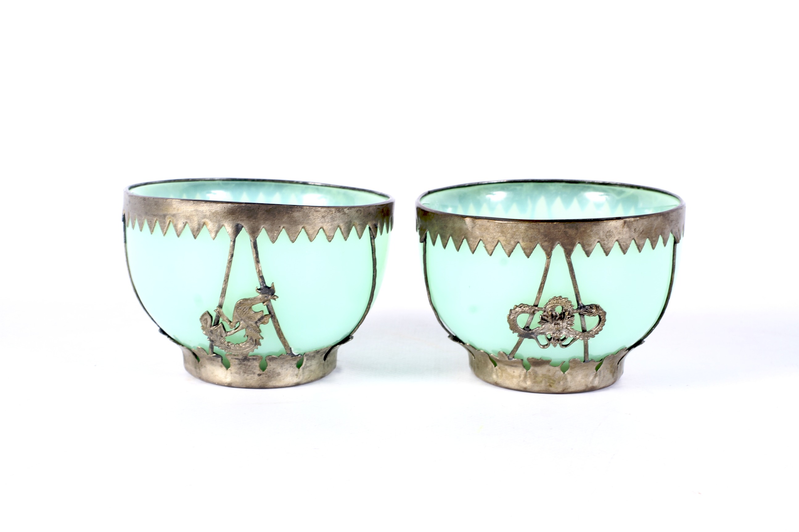 A small pair of early 20th century Chinese white metal mounted pale-green glass bowls.