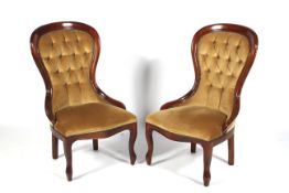 A pair of contemporary mahogany framed spoon button back nursing chairs.