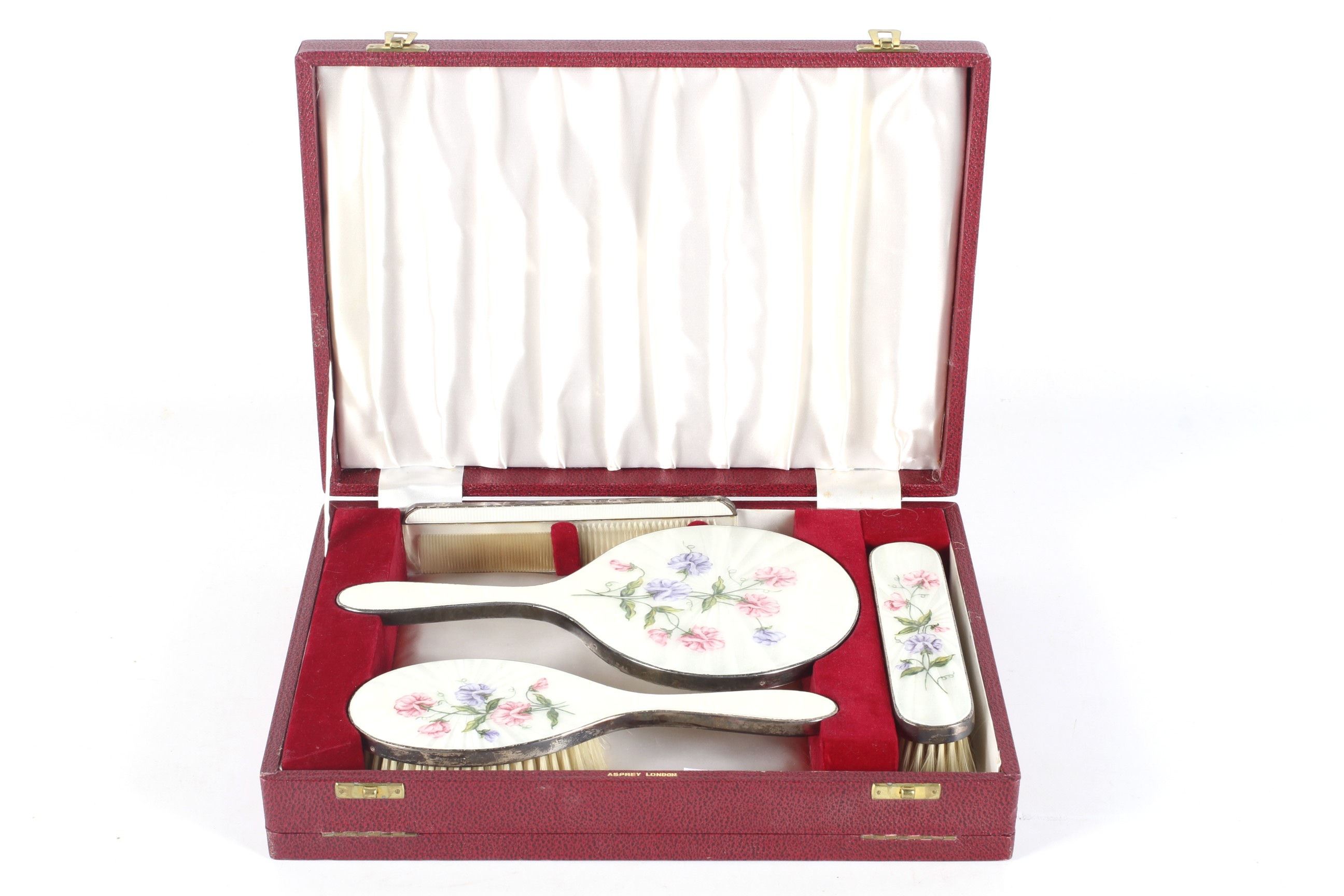 A four-piece silver and enamel dressing table set retailed by Asprey, London.