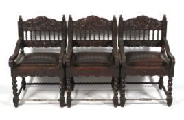 A set of three 20th century heavily carved Portuguese style colonial elbow chairs.