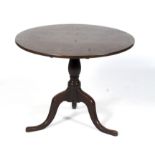 A Georgian circular oak tilt top tripod table raised on a baluster column to outswept cabriole