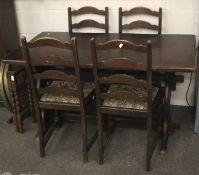 A mid-century stained wooden dining table and four ladder back dining chairs.