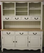 A contemporary painted dresser, with open shelves above four drawers.