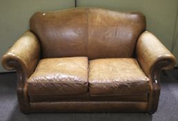 A worn brown leather sofa with arched back, scrolled stud work arm rests,